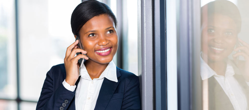 Young lady in business suit is smiling while talking on her cell phone.