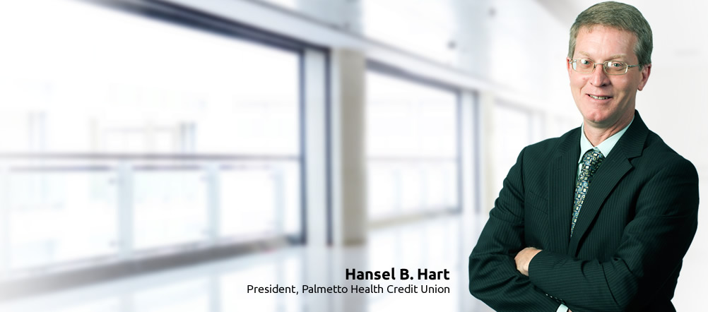 Palmetto Health Credit Union President, Hansel B. Hart, is smiling and standing with arms crossed.
